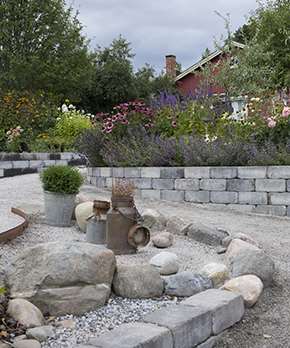 En trädgård men mycket blommor och en mur byggd av Labyrint Maxi. 