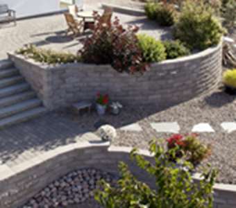 Trädgård med murar, trappa, trädgårdsgång och dekormaterial.