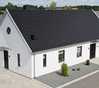 Vitt hus byggt med murblock och med Benders svarta takpannor på taket.