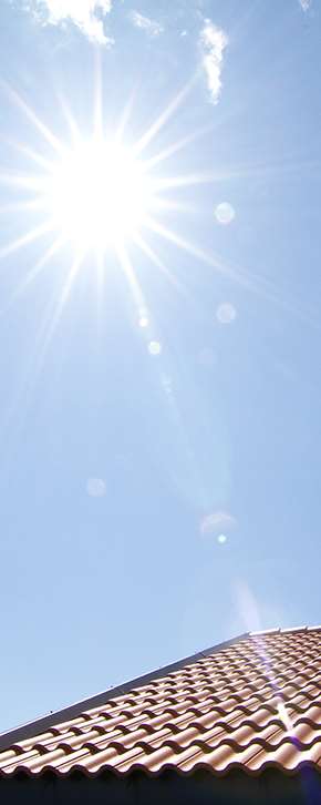 Sol på en klarblå himmel med ett tak som anas i nederkant.